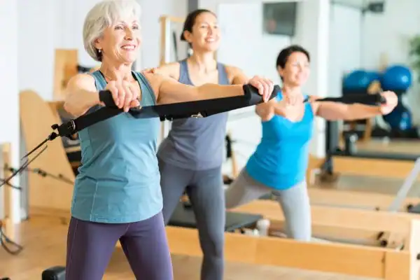 Toning Arms After 60: Empowering Womens Fitness Through Effective Weight Training 2 older woman doing weight training Crawley and resistance in the gym to tone upper arms