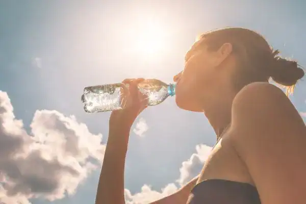 Hydration: The Secret Ingredient for a Toned Stomach and Enhanced Fitness 3 Image of woman drinking water to hydrate Crawley after run.
